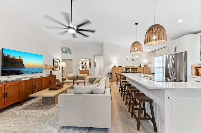 living area with a ceiling fan, light wood-style floors, and vaulted ceiling