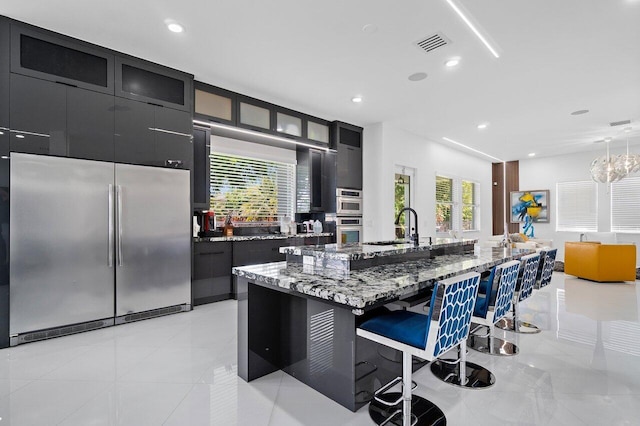682 Cresta Cir, West Palm Beach, FL 33413 - kitchen featuring appliances with stainless steel finishes, a sink, dark cabinetry, a kitchen bar, and recessed lighting