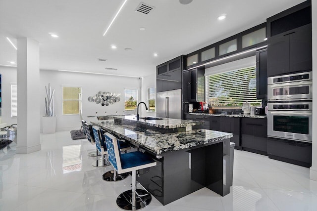 682 Cresta Cir, West Palm Beach, FL 33413 - kitchen featuring stainless steel appliances, dark cabinets, a large island, a breakfast bar area, and recessed lighting