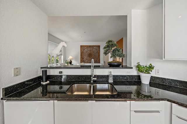 11011 Legacy Ln Unit 306, Palm Beach Gardens, FL 33410 - kitchen featuring a sink, white cabinetry, dark stone counters, and a textured wall