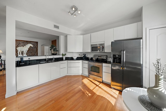 11011 Legacy Ln Unit 306, Palm Beach Gardens, FL 33410 - kitchen featuring appliances with stainless steel finishes, a sink, dark countertops, light wood finished floors, and white cabinetry