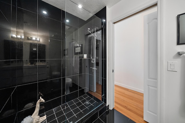 11011 Legacy Ln Unit 306, Palm Beach Gardens, FL 33410 - full bathroom with a shower stall, wood finished floors, toilet, a textured ceiling, and baseboards