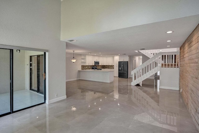 unfurnished living room with stairs, light marble finish flooring, recessed lighting, and baseboards
