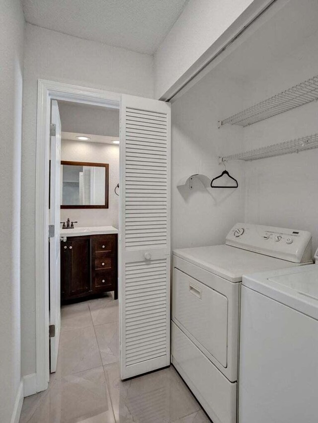 clothes washing area with washing machine and dryer, light marble finish flooring, and baseboards