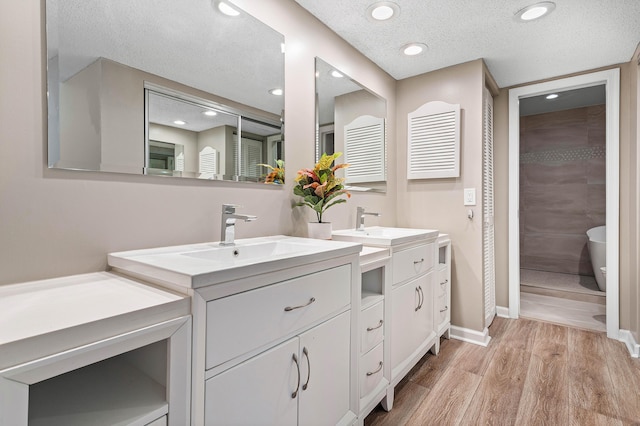 22924 Ironwedge Dr, Boca Raton, FL 33433 - full bathroom with two vanities, wood finished floors, a soaking tub, recessed lighting, and a textured ceiling