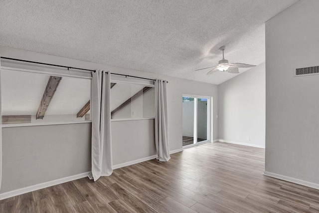 unfurnished bedroom with lofted ceiling, wood finished floors, a textured ceiling, access to exterior, and baseboards