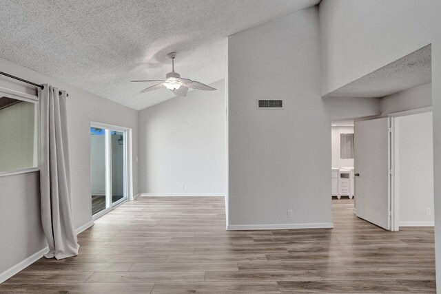 spare room with vaulted ceiling, ceiling fan, a textured ceiling, wood finished floors, and baseboards