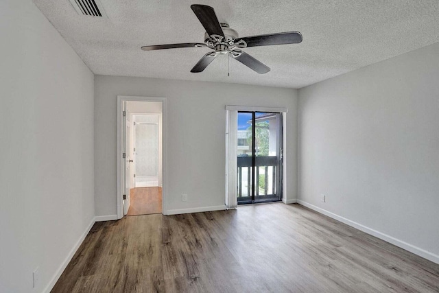 empty room with wood finished floors, a textured ceiling, ceiling fan, and baseboards