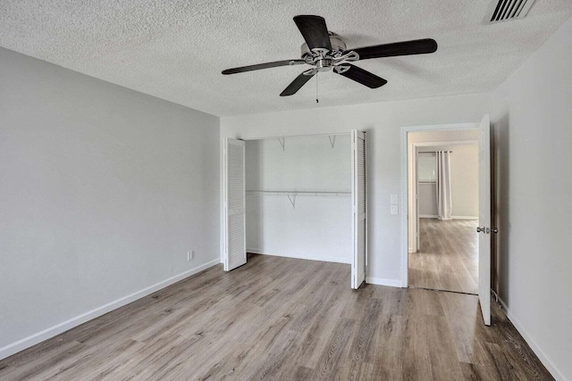 unfurnished bedroom with wood finished floors, a closet, a textured ceiling, ceiling fan, and baseboards