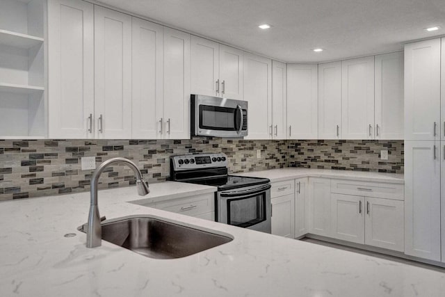 kitchen featuring stainless steel appliances, a sink, open shelves, white cabinetry, and recessed lighting