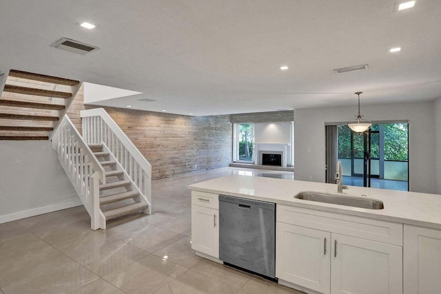 kitchen featuring stainless steel dishwasher, a sink, white cabinetry, hanging light fixtures, and plenty of natural light