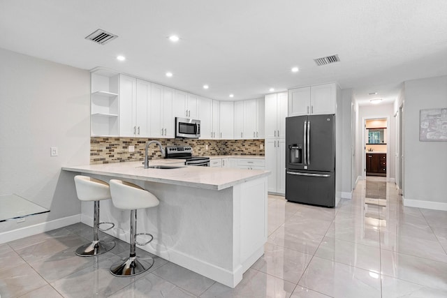 22924 Ironwedge Dr, Boca Raton, FL 33433 - kitchen featuring appliances with stainless steel finishes, open shelves, a sink, a peninsula, and decorative backsplash