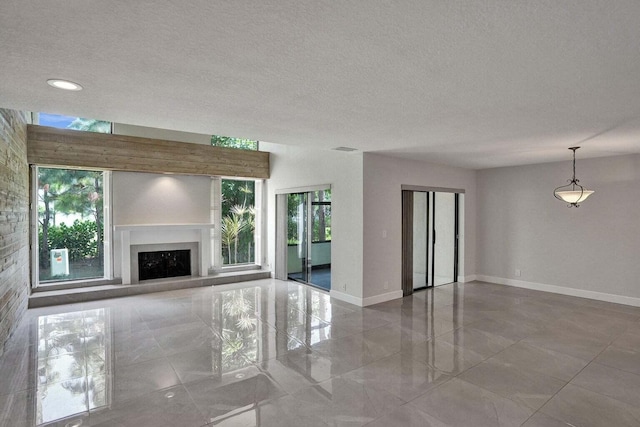 unfurnished living room with baseboards, a fireplace, and a textured ceiling