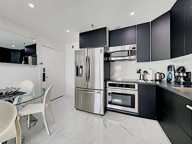 3100 Parkway Blvd Unit 310, Kissimmee, FL 34747 - kitchen featuring appliances with stainless steel finishes, dark cabinetry, modern cabinets, light marble finish flooring, and stainless steel countertops