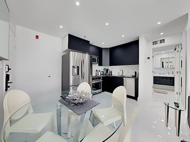 3100 Parkway Blvd Unit 310, Kissimmee, FL 34747 - kitchen featuring dark cabinetry, appliances with stainless steel finishes, modern cabinets, light marble finish floors, and a sink