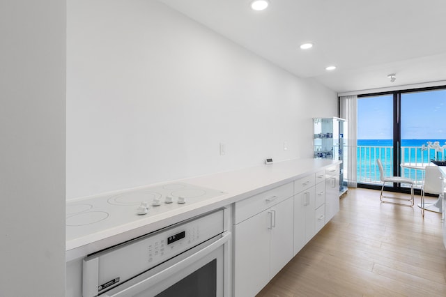 3360 S Ocean Blvd Unit 5Fii, Palm Beach, FL 33480 - kitchen featuring white appliances, floor to ceiling windows, light countertops, white cabinets, and light wood-style flooring