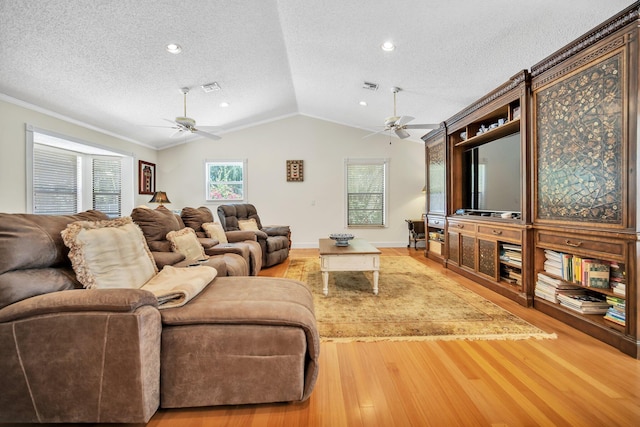 living room with ceiling fan, a textured ceiling, wood finished floors, crown molding, and vaulted ceiling