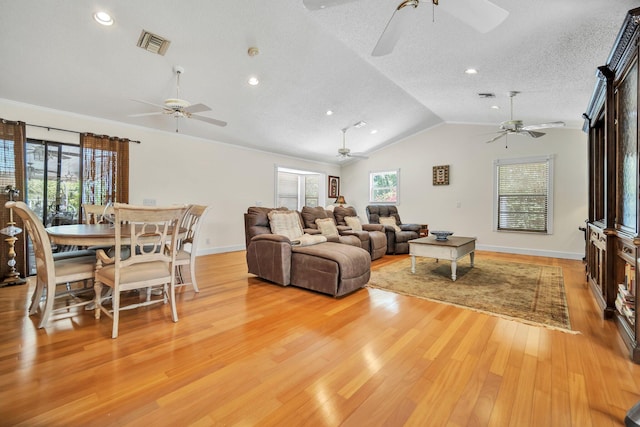 living area featuring ceiling fan, plenty of natural light, lofted ceiling, a textured ceiling, and recessed lighting