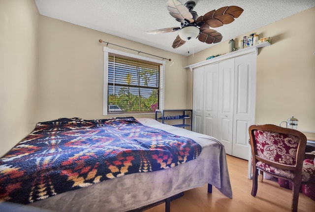 bedroom featuring wood finished floors, a closet, a ceiling fan, and a textured ceiling