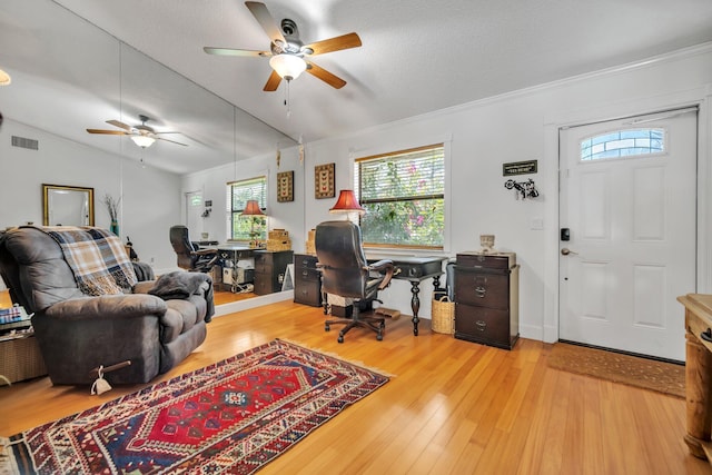 home office featuring ceiling fan, plenty of natural light, light wood-style floors, vaulted ceiling, and a textured ceiling
