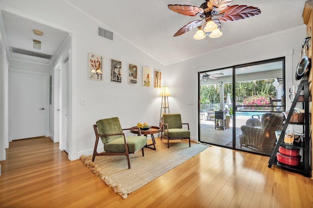 living area with ceiling fan, light wood-type flooring, and ornamental molding