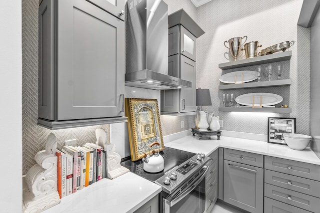 kitchen with wall chimney range hood, gray cabinets, open shelves, light countertops, and tasteful backsplash