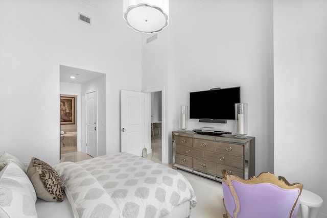 bedroom featuring a high ceiling, connected bathroom, and crown molding