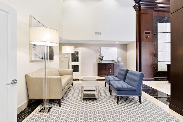 living room with baseboards, inlaid floor details, marble tiled floors, and a high ceiling