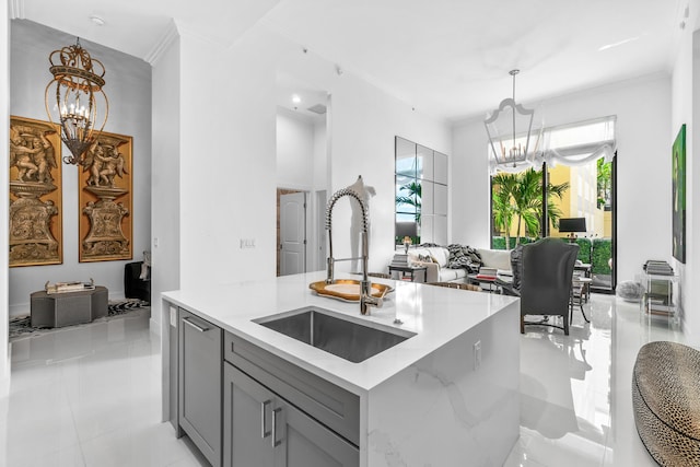 kitchen with a chandelier, a sink, gray cabinetry, crown molding, and pendant lighting