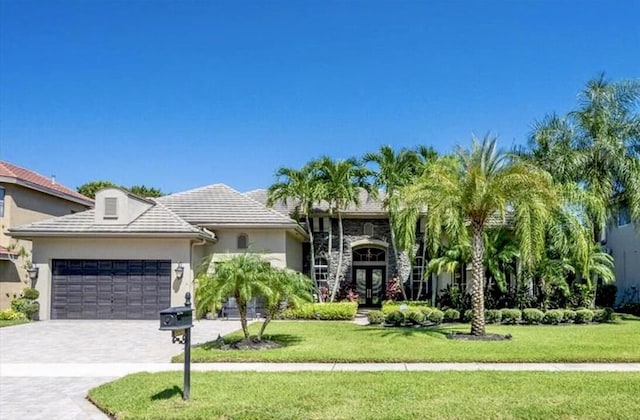 view of front facade featuring an attached garage, a front lawn, decorative driveway, and stucco siding
