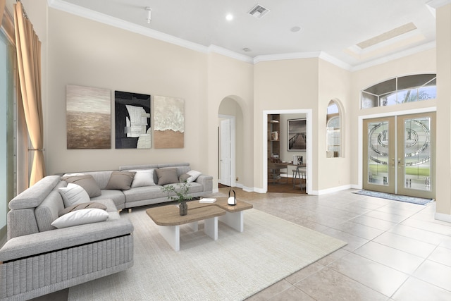 living room featuring ornamental molding, arched walkways, tile patterned flooring, baseboards, and french doors