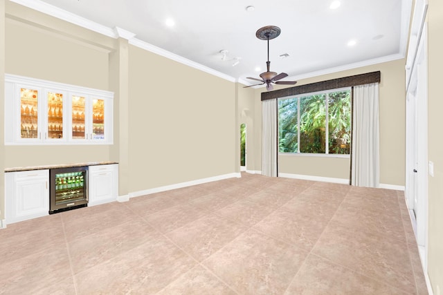 unfurnished living room with beverage cooler, a ceiling fan, ornamental molding, a dry bar, and light tile patterned floors