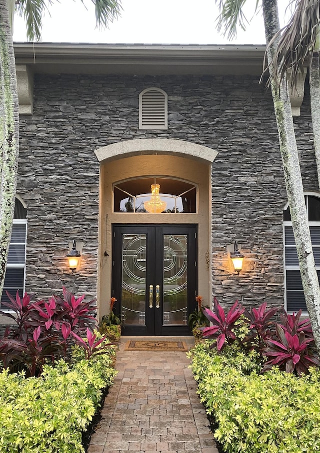 property entrance featuring french doors, stone siding, and stucco siding