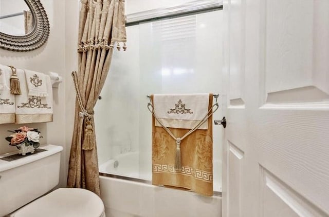 full bath with toilet and shower / bath combination with glass door