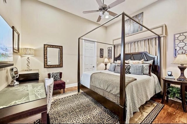 bedroom featuring wood finished floors, baseboards, ceiling fan, and a towering ceiling