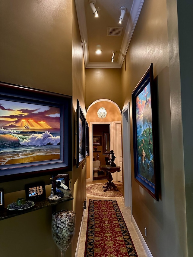 hall with ornamental molding, baseboards, and a high ceiling