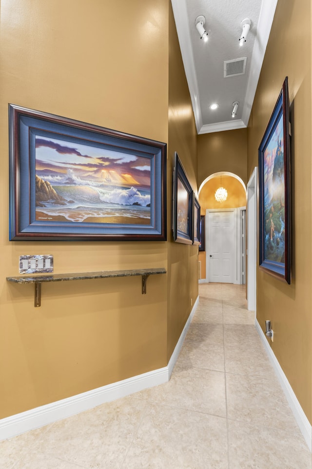 corridor with ornamental molding, light tile patterned floors, baseboards, and a chandelier