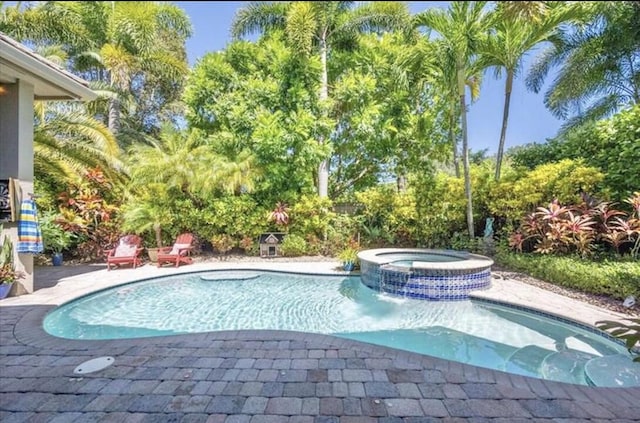 view of swimming pool featuring a pool with connected hot tub and a patio