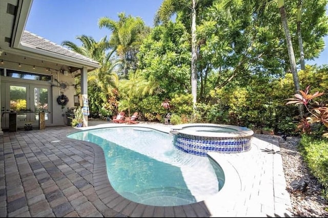 view of swimming pool featuring a patio, french doors, and a pool with connected hot tub