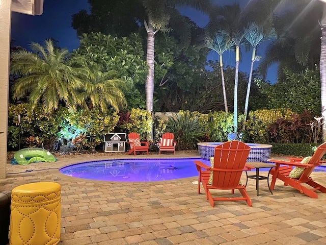 pool at twilight with a patio area and an outdoor pool