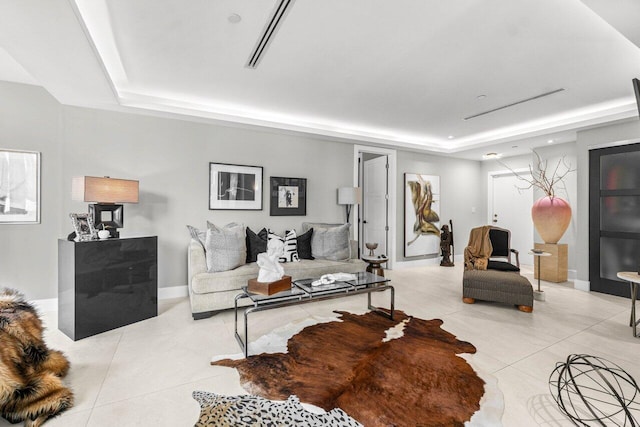 living area featuring a raised ceiling, light tile patterned floors, and baseboards