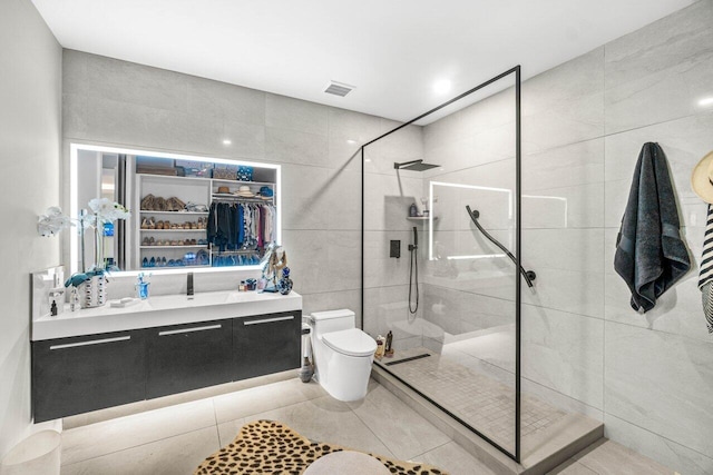 full bathroom with toilet, a walk in shower, tile walls, vanity, and tile patterned flooring