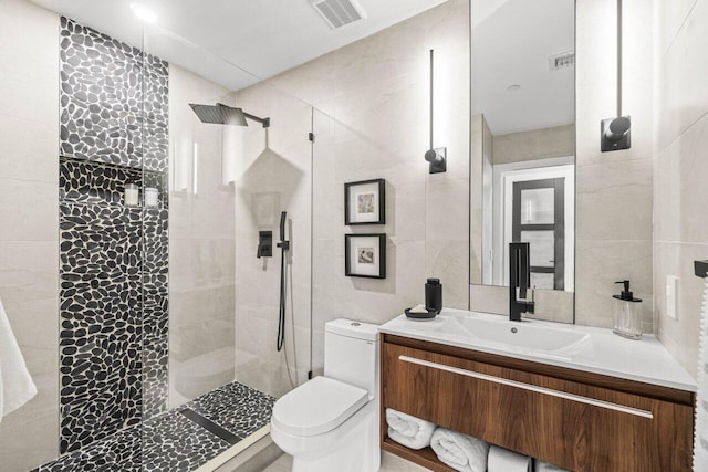 bathroom featuring tile walls, walk in shower, toilet, and vanity