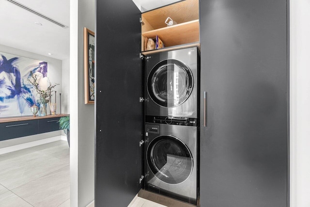 laundry area with estacked washer and dryer and baseboards