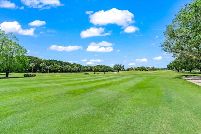 view of property's community featuring golf course view, a yard, and view of wooded area