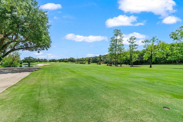 surrounding community featuring golf course view, a lawn, view of wooded area, and a water view