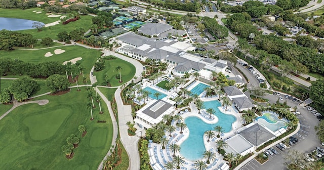 aerial view of property and surrounding area with a pool, a golf club, and a nearby body of water
