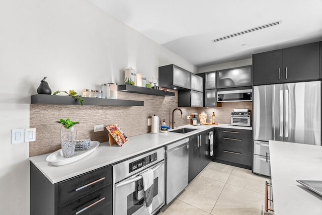 kitchen featuring a sink, stainless steel appliances, open shelves, light countertops, and decorative backsplash