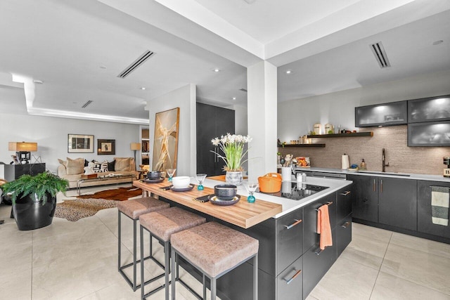 kitchen with a sink, a center island, light tile patterned floors, light countertops, and recessed lighting