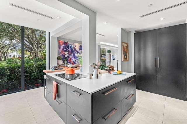 kitchen featuring modern cabinets, black electric stovetop, light tile patterned floors, a kitchen island, and light countertops